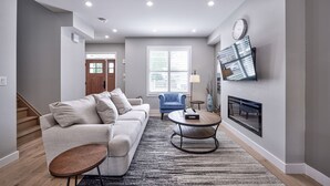 A modern living room with a sofa, coffee table, and a fireplace. - Cottage featuring Lake view balcony, private elevator and 3 en-suites! (Fort Erie)