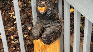 Una escultura de oso de madera sobre un banco.