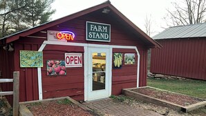 Un edificio de madera roja con un letrero que dice 'FARM STAND' y 'ABIERTO'.