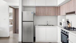 Una cocina moderna con armarios blancos, un refrigerador de acero inoxidable, un microondas y una estufa a gas.
