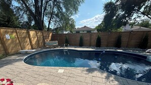 A swimming pool with a wooden deck and a wooden fence.