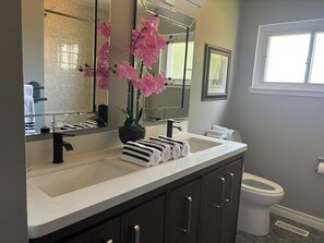 A modern bathroom with a white sink, dark cabinets, a black faucet, a toilet, and a window. - Comfortable & Bright 4BD Stay Near Airport & Downtown Toronto w/opt pool access  (Mississauga)