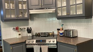 A kitchen with grey cabinets, a stainless steel stove, and a toaster.