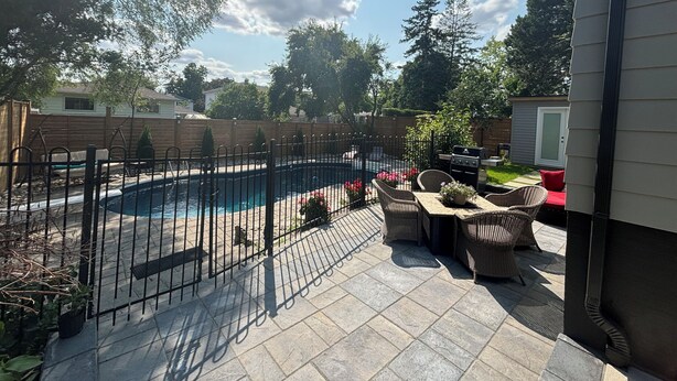 A backyard with a swimming pool, patio furniture, and a wooden fence.