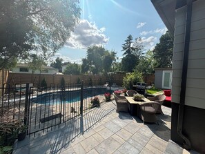 A backyard with a swimming pool, patio furniture, and a wooden fence.