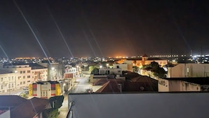 A nighttime cityscape with illuminated buildings and a prominent bridge in the distance.