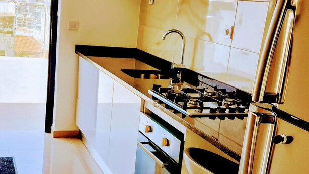 A modern kitchen with stainless steel appliances, a large window, and a view of the city.