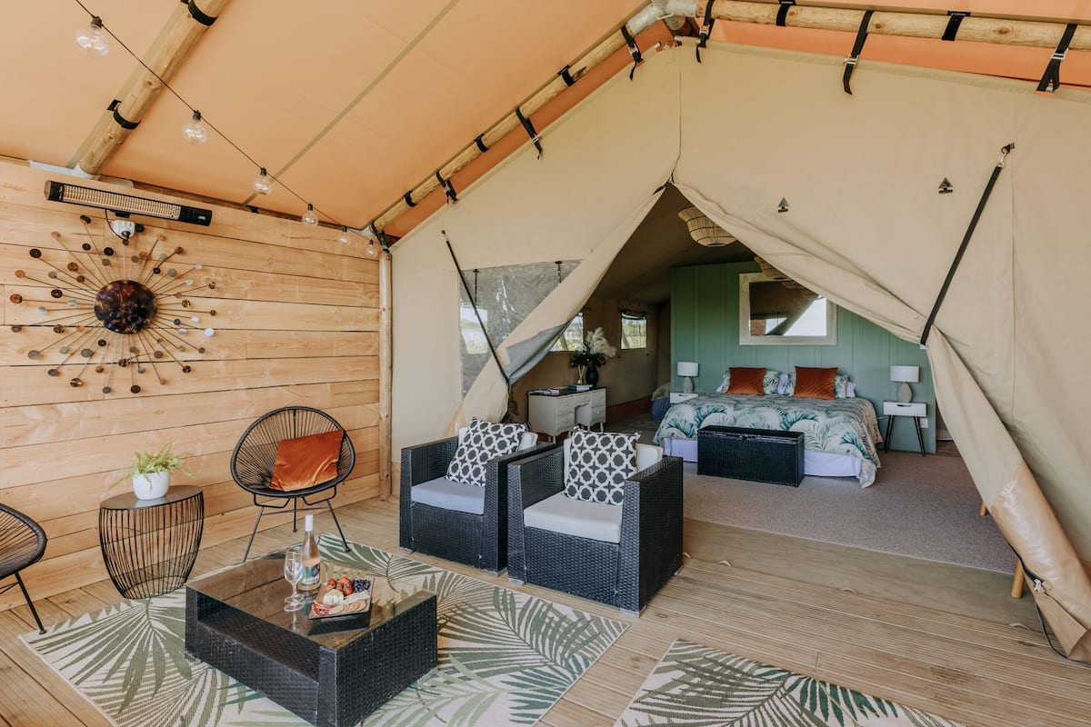 Un hébergement sous tente comprenant un espace repas, deux canapés, une table basse et un lit avec vue.