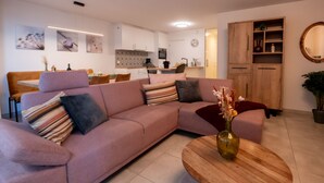 A modern living room with a pink sofa, a wooden coffee table, and a dining area in the background. - La Marée with parking & lateral seaview by Interhome (Blankenberge)