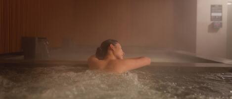 Eine Person entspannt sich in einer Hot Tub vor einer Holzwand mit Bedienfeld im Hintergrund.
