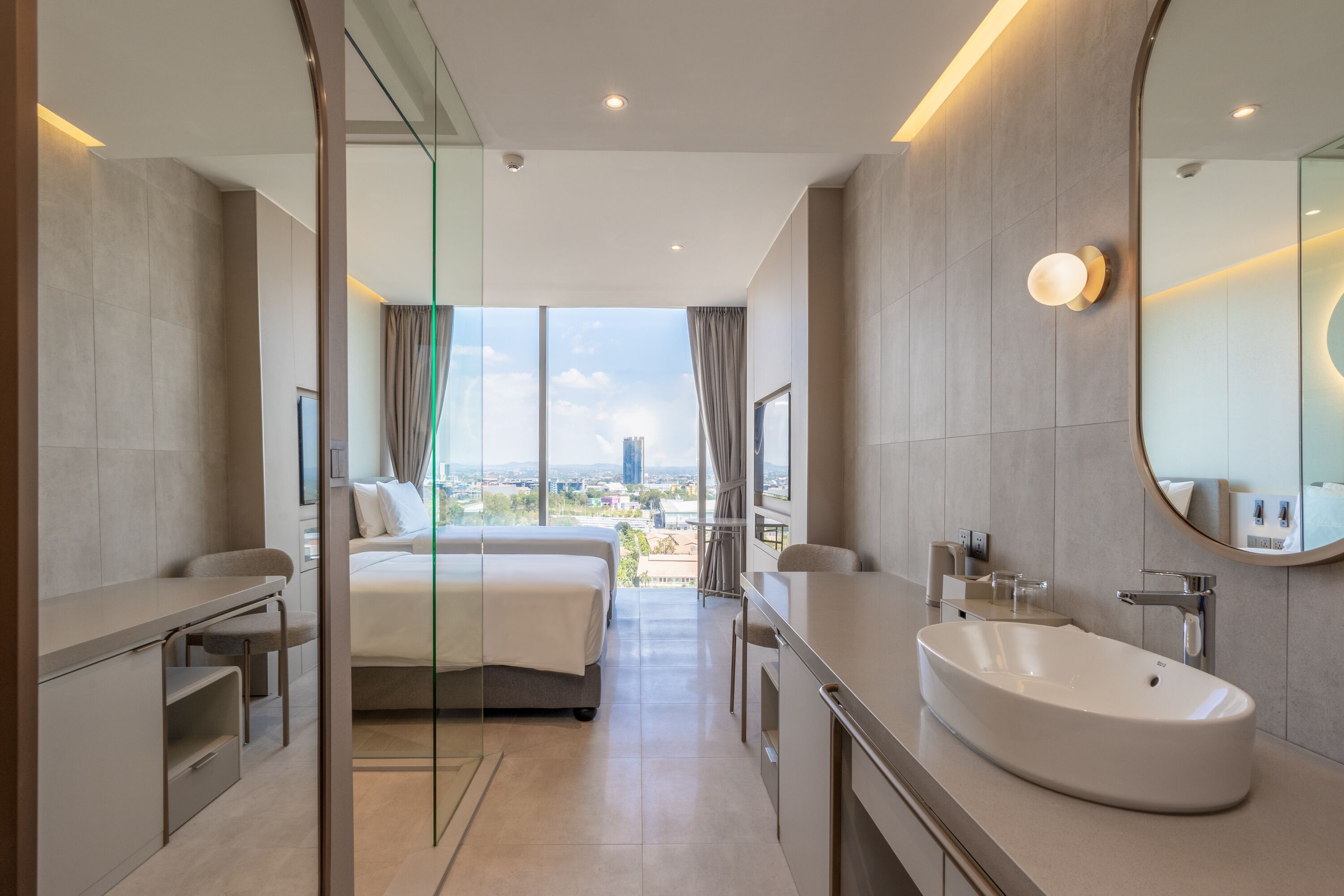 Una habitación de hotel moderna con una cama grande, un baño con un lavamanos amplio y vistas a la ciudad.