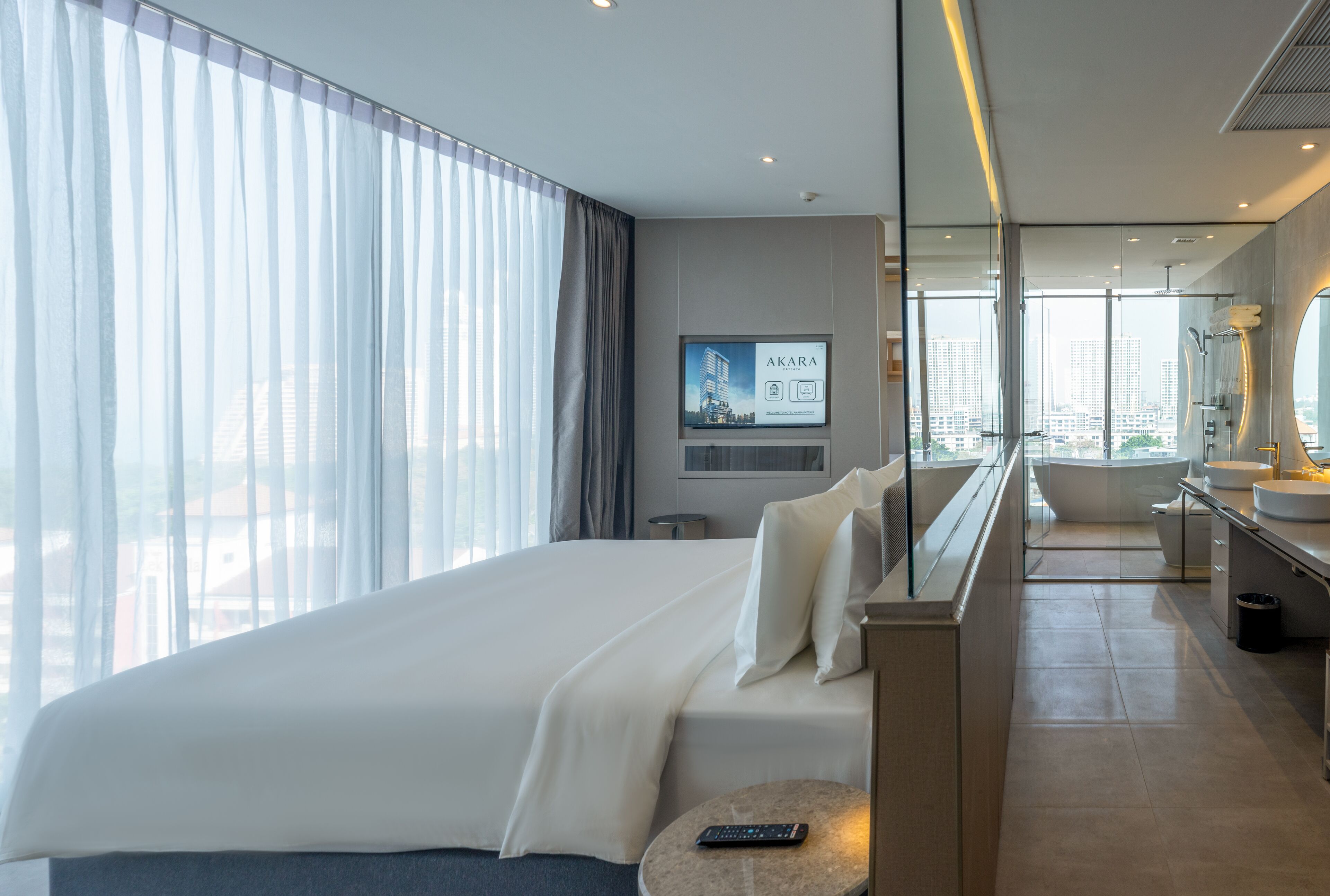 Una habitación de hotel moderna con una cama grande, un baño con bañera y vistas a la ciudad.