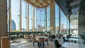 A spacious indoor dining area with large windows, multiple tables, and chairs. - Akara Hotel Pattaya (Pattaya)