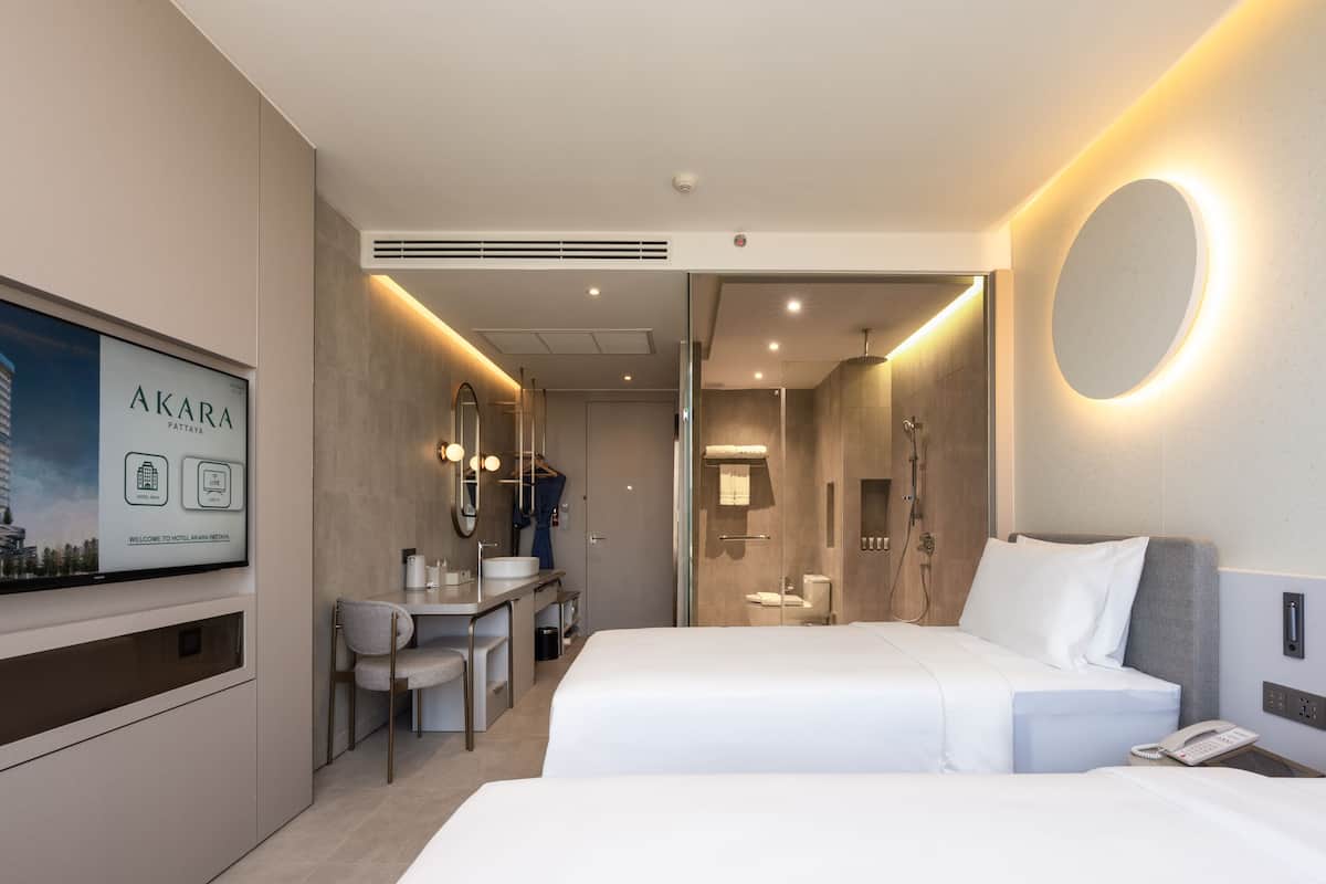A modern hotel room with a bed, bedside table, and a desk with a chair.