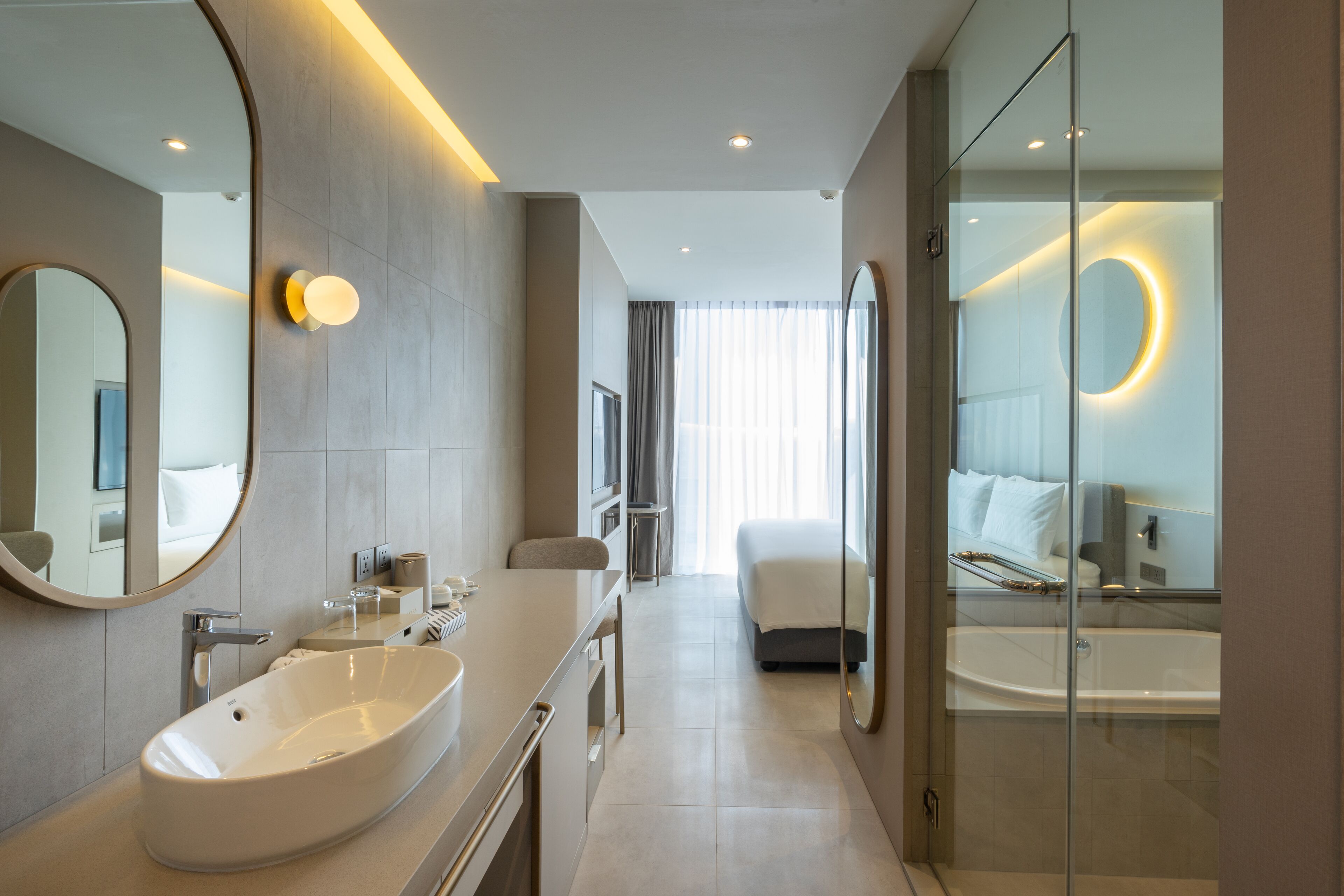 A modern hotel bathroom with a large sink, mirror, and bathtub.