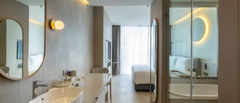 A modern hotel bathroom with a large sink, mirror, and bathtub.