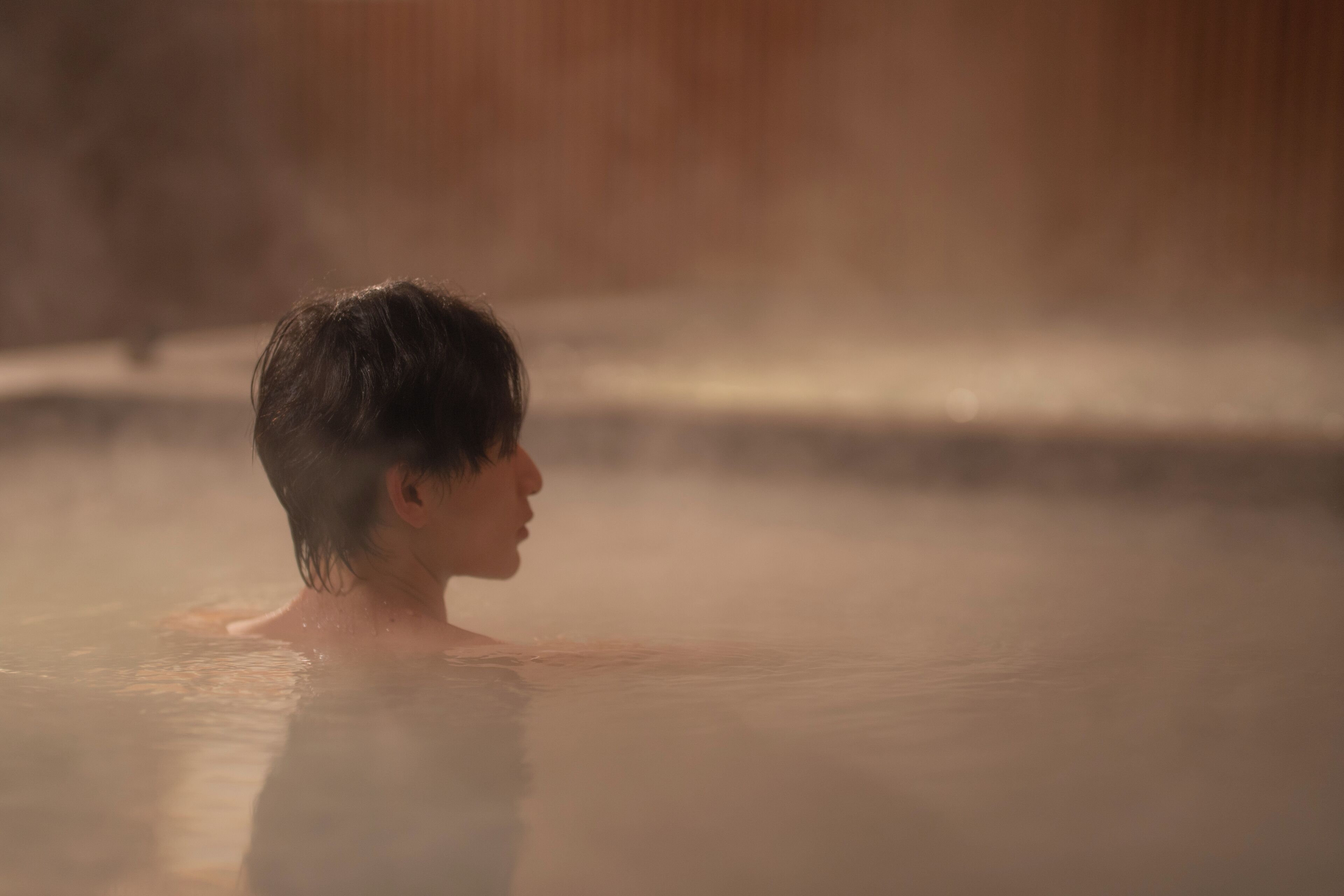 A person in a hot spring with steam rising from the water.