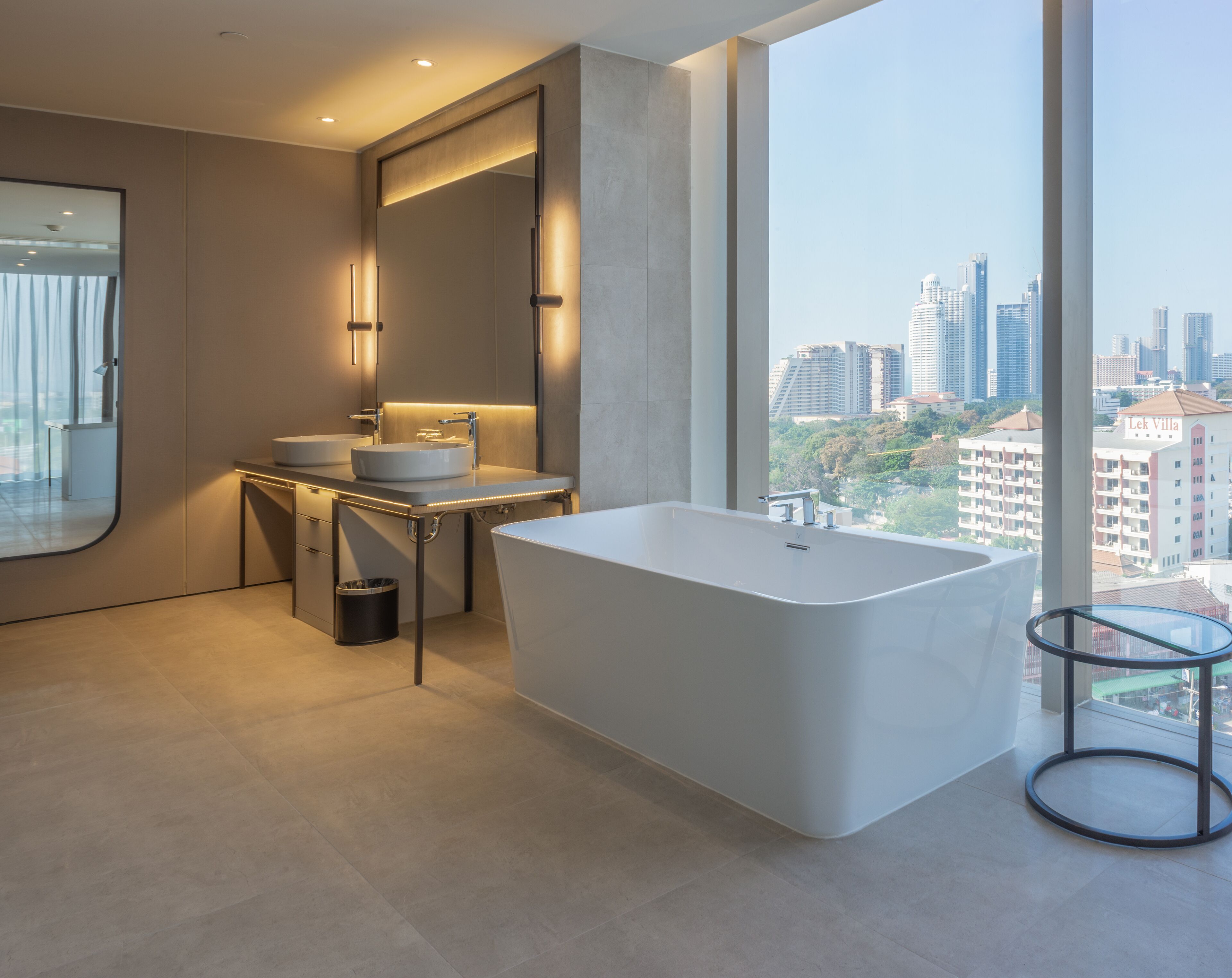 Un baño moderno con una bañera independiente, un tocador con doble lavabo y un espejo grande.