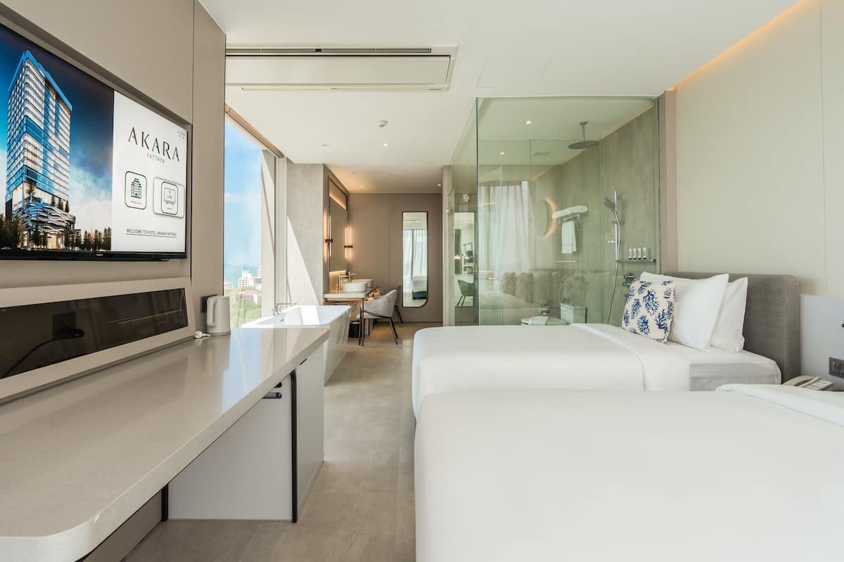 A modern hotel room with a large bed, a desk, and a bathroom with a glass shower.