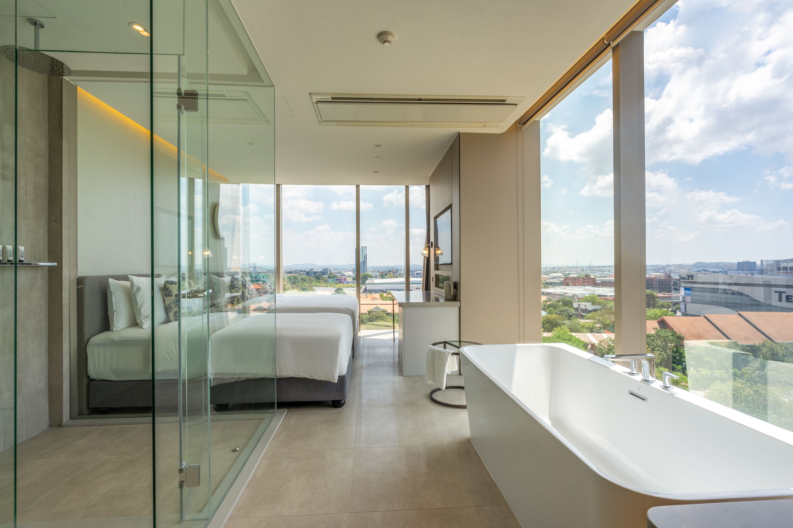 A modern hotel room with a large window, a bathtub, and a bed.