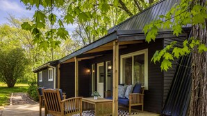 A wooden deck with outdoor furniture, a covered porch, and a view of the surrounding trees. - Lakefront with Lake Access•Hot Tub•Firepit•Pets (Rockbridge)