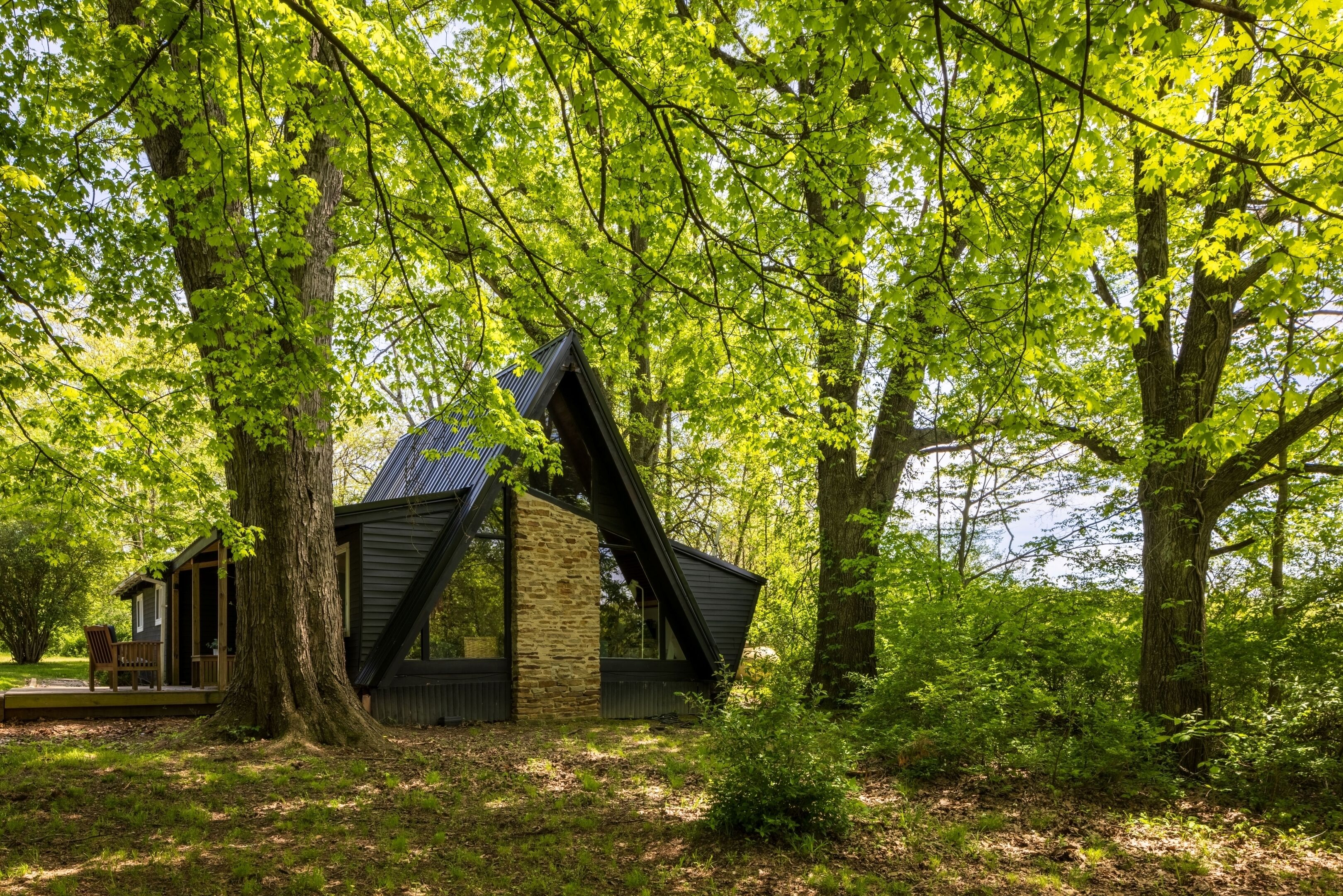 A cabin with a sloped roof, surrounded by trees and a wooden deck.