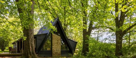 A cabin with a sloped roof, surrounded by trees and a wooden deck.