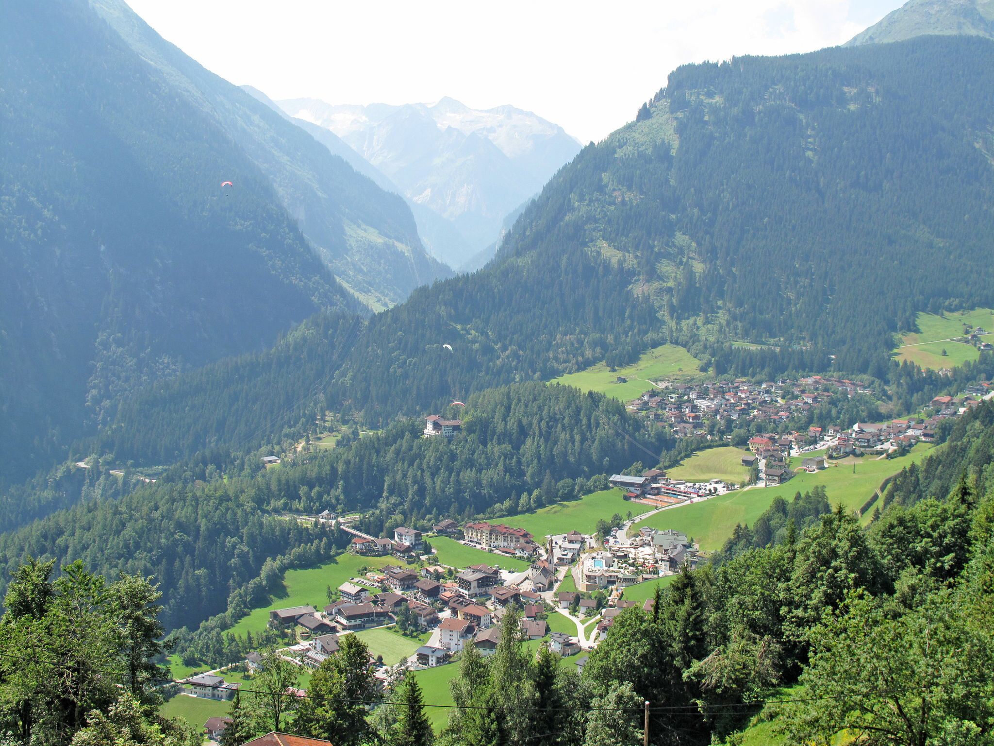 A mountainous village with traditional houses, a winding road, and a valley.