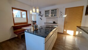 Une cuisine moderne dotée d’un îlot central, de planchers en bois et de luminaires suspendus.