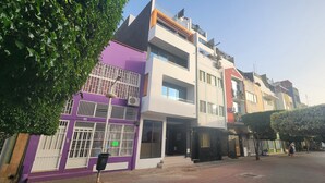 A multi-story building with a purple facade, large windows, and a gated entrance. - Flamingo Plateau. 1A Apt on Rua Pedonal. Praia Central_ Near cafes & shops (Praia)