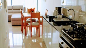 A modern kitchen with a stove, oven, and washing machine. There is a dining area with a table and chairs. - Flamingo Plateau. 1A Apt on Rua Pedonal. Praia Central_ Near cafes & shops (Praia)
