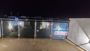 A balcony with a glass door leading to a street view at night. - Flamingo Plateau. 1A Apt on Rua Pedonal. Praia Central_ Near cafes & shops (Praia)