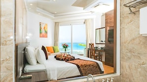 Una habitación de hotel moderna con una cama grande, una bañera y vista al mar.