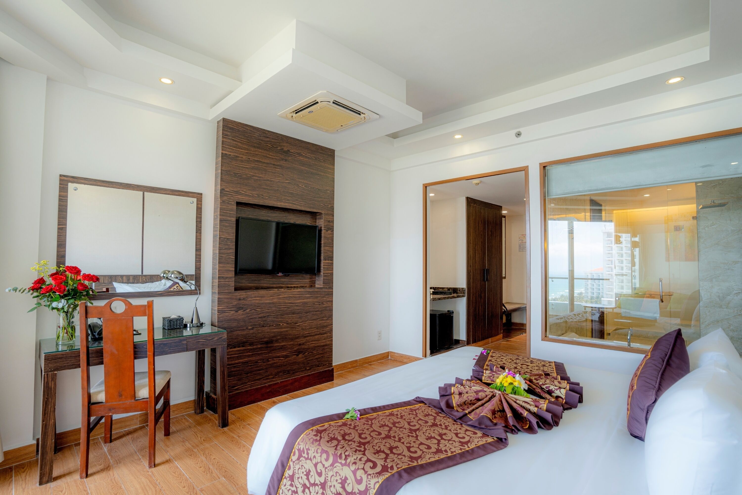 Una habitación de hotel con cama, escritorio, televisor y un amplio ventanal.