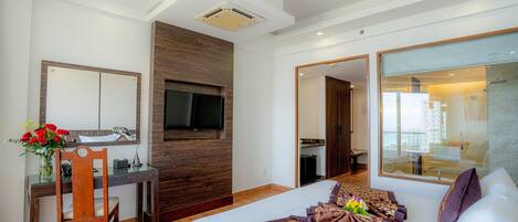 Una habitación de hotel con cama, escritorio, televisor y un amplio ventanal.