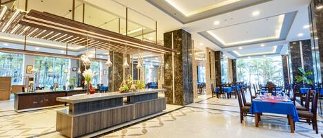 A modern hotel lobby with a reception desk, seating area, and large windows.