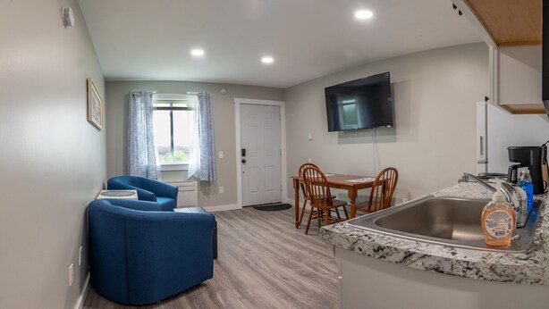 A compact kitchen with a granite countertop, a built-in sink, and a dining area with a table and chairs. - Charming Apt_Open Green Space on Front to Relax and Sunbath (Hancock)