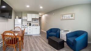 A compact living space with a kitchenette, a dining area with wooden chairs, and two blue sofas. - Charming Apt_Open Green Space on Front to Relax and Sunbath (Hancock)