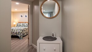 A bedroom with a bed, a bedside table, a mirror, and a door leading to another room. - Charming Apt_Open Green Space on Front to Relax and Sunbath (Hancock)