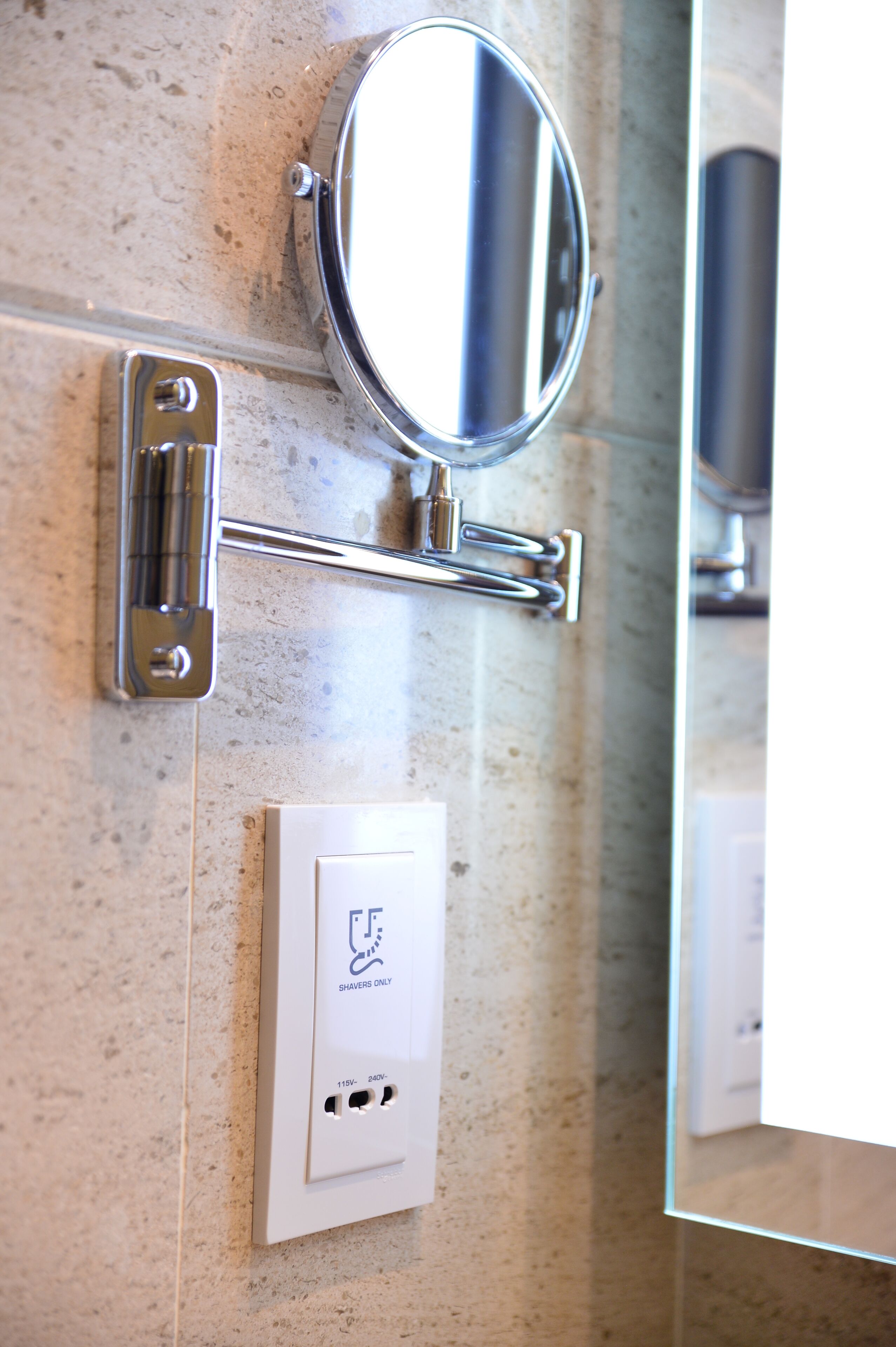 A bathroom with a mirror, a towel rack, and a power outlet labeled "Shavers Only".
