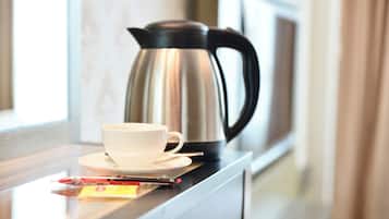A stainless steel coffee pot and a white cup on a countertop.