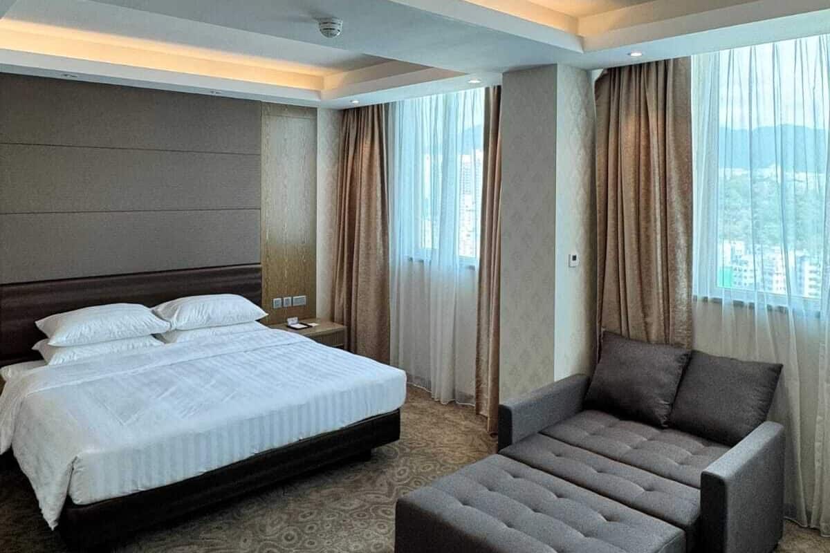 Ein Hotelzimmer mit einem großen Bett, einer Couch und einem gemusterten Teppich.