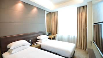 A hotel room with two beds, a desk, and a TV.
