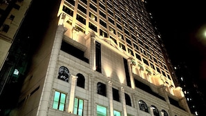 A high-rise building with multiple floors, large windows, and a prominent entrance with an arched design. - Kew Green Hotel Mongkok (Kowloon)