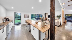 A modern kitchen with a wooden island, large windows, and a view of the outdoors. - Escape to a unique house located in the world-renowned surf spot of Bells Beach! (Bells Beach)