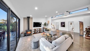 A modern living room with a fireplace, a large TV, and a comfortable seating area. - Escape to a unique house located in the world-renowned surf spot of Bells Beach! (Bells Beach)