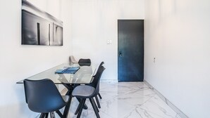 Un espace repas moderne avec une table en verre, des chaises noires et un tableau minimaliste accroché au mur.