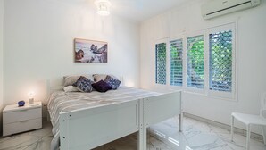 Une chambre à coucher avec un lit, une table de chevet et une fenêtre donnant sur un paysage verdoyant.
