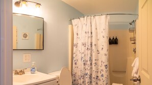 Une salle de bain équipée de toilettes, d’un lavabo, d’une douche et d’un miroir.