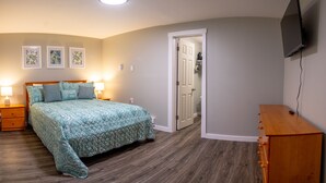 Une chambre à coucher avec un lit, des lampes de chevet, un téléviseur fixé au mur et une porte donnant sur un placard.
